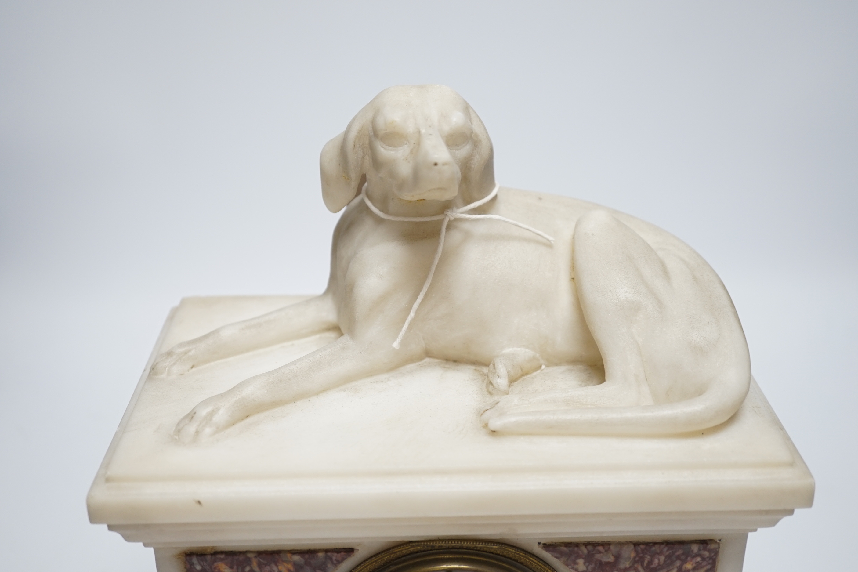 A 19th century French alabaster and rouge marble ‘hound’ mantel timepiece, 29cm tall